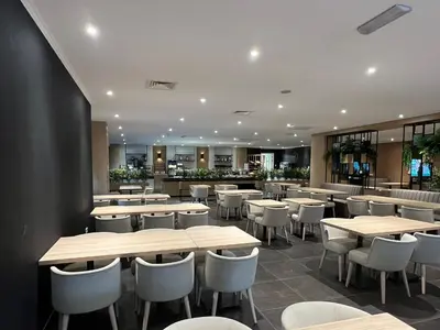 a restaurant with wooden tables and white chairs at XO Hotels Blue Square in Amsterdam