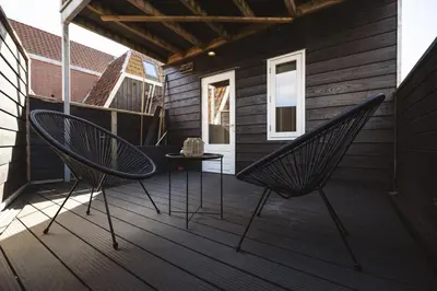 a patio with two chairs and a table on a deck at Pakhuys 15 in Alkmaar