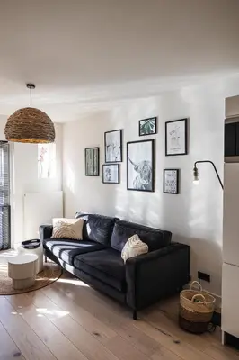 a living room with a black couch and some pictures on the wall at Pakhuys 15 in Alkmaar