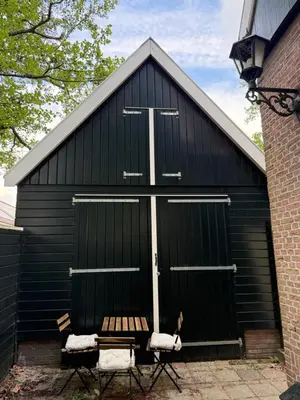 a black building with two chairs in front of it at Stolp & Stay in Broek in Waterland