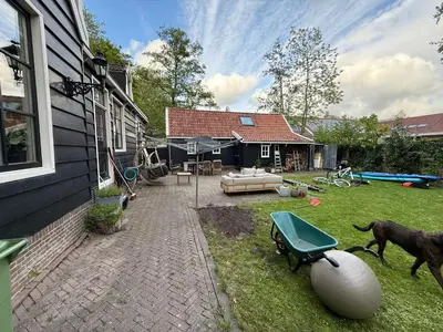 a house with a yard with a dog and a wheelbarrow at Stolp & Stay in Broek in Waterland