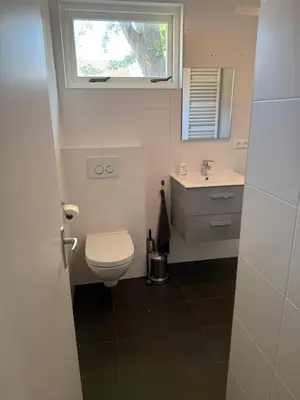 a bathroom with a toilet and a sink and a window at Stolp & Stay in Broek in Waterland