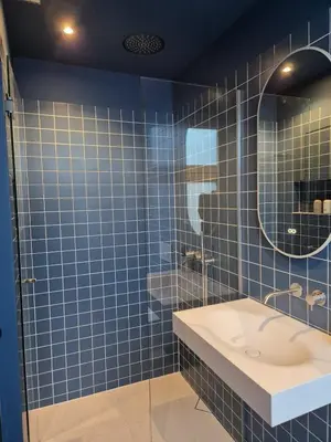 a blue tiled bathroom with a sink and a mirror at Suite Palette in Amsterdam