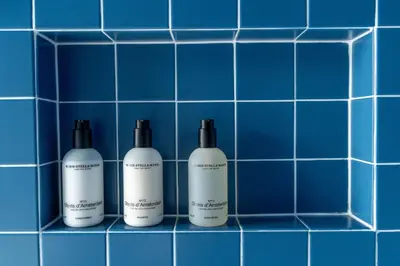 three shampoo bottles sitting on a blue tiled wall at Suite Palette in Amsterdam