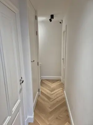 a hallway with white walls and a wooden floor at Suite Palette in Amsterdam