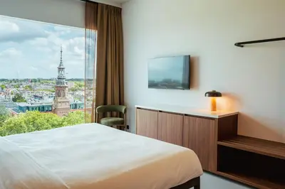 a hotel room with a bed and a large window at Hotel V Oosterpark in Amsterdam