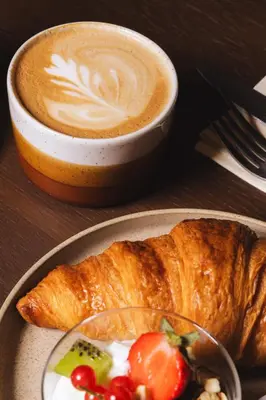 a cup of coffee next to a plate of food at Hotel V Oosterpark in Amsterdam