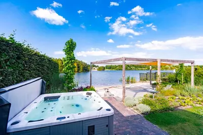 a hot tub in a garden next to a body of water at Watervilla van Francke by Droomvilla in Ons Belang