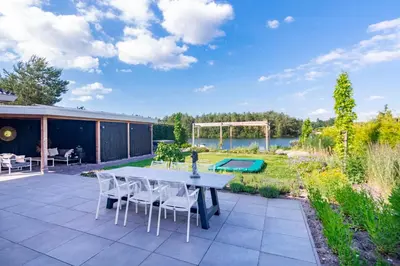 a patio with a table and chairs and a garden at Watervilla van Francke by Droomvilla in Ons Belang