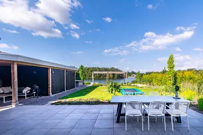 a patio with a table and chairs and a yard at Watervilla van Francke by Droomvilla in Ons Belang