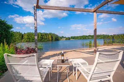 a table and chairs on a patio next to a lake at Watervilla van Francke by Droomvilla in Ons Belang