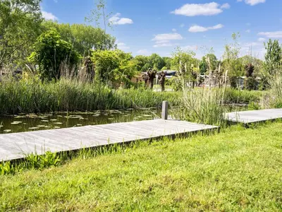a wooden dock in a pond with an elephant in the background at Holiday Home in Oud Ade near Kaag Lakes in Oud-Ade