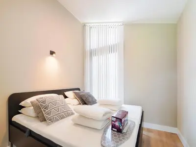a bedroom with a bed with white pillows and a window at Holiday Home near Kaag Lakes and Leiden Canals in Oud-Ade