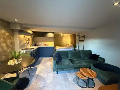 a living room with a green couch and a kitchen at Katwijks geluk in Katwijk aan Zee