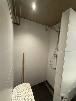 a bathroom with a shower with a chair in it at Katwijks geluk in Katwijk aan Zee