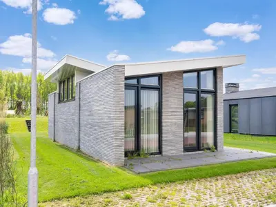 a small house with glass doors on a lawn at Holiday Home in Oud Ade near Kaag Lakes in Oud-Ade