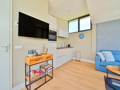 a living room with a blue couch and a flat screen tv at Holiday Home in Oud Ade near Kaag Lakes in Oud-Ade