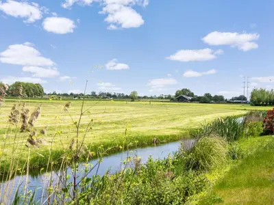 a field with a stream in the middle of a field at Holiday Home Oud Ade near Kaag Lakes in Oud-Ade