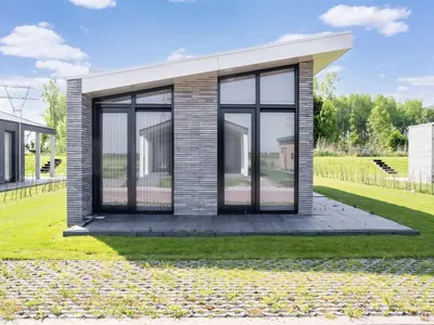 a small house with glass doors on a lawn at Holiday Home in Oud Ade near Kaag Lakes in Oud-Ade