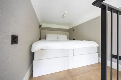 a bedroom with a white bed in a attic at Huize Randenbroek Amersfoort in Amersfoort