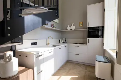 a kitchen with white cabinets and a black staircase at Huize Randenbroek Amersfoort in Amersfoort