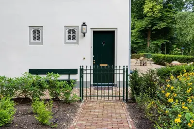 a white house with a green door and a brick walkway at Huize Randenbroek Amersfoort in Amersfoort