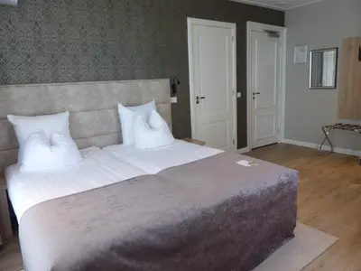 a bedroom with a large bed with white pillows at Herberg Welgelegen in Katwijk
