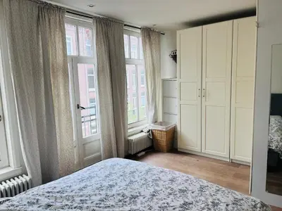a bedroom with a bed and two large windows at Cozy museum area home in Amsterdam