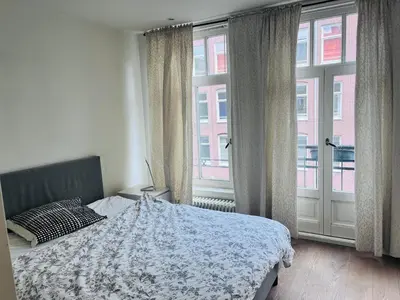 a bedroom with a bed and two large windows at Cozy museum area home in Amsterdam