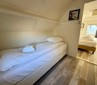a bed with white sheets and pillows in a room at Noordwijk-sur-mer in Noordwijk aan Zee
