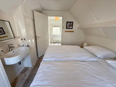 a white bedroom with a bed and a sink at Noordwijk-sur-mer in Noordwijk aan Zee