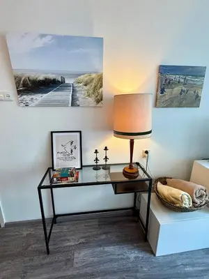 a desk with a lamp and pictures on the wall at Noordwijk-sur-mer in Noordwijk aan Zee