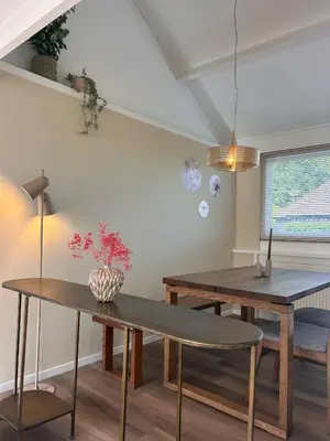 a dining room with two tables and a vase with flowers at Het Dijkhuysje by ZILT in Warmenhuizen