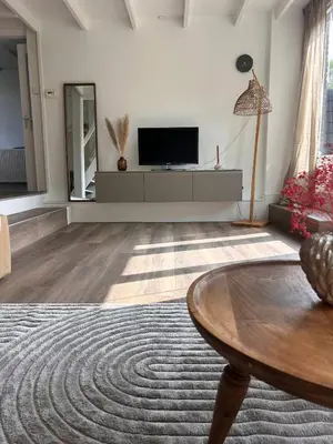 a living room with a television and a table at Het Dijkhuysje by ZILT in Warmenhuizen