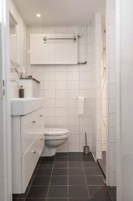 a white bathroom with a toilet and a sink at Het Dijkhuysje by ZILT in Warmenhuizen