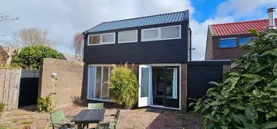 a black house with a picnic table in front of it at Het Dijkhuysje by ZILT in Warmenhuizen
