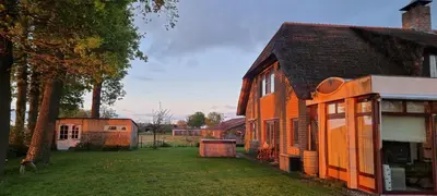 an orange building with a yard next to a house at B&B Krachtwijk in Soest