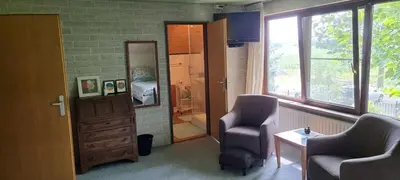 a room with two chairs and a mirror and a bedroom at B&B Krachtwijk in Soest