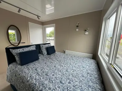 a bedroom with a bed and a large window at Bed en B-ootje in Bunschoten