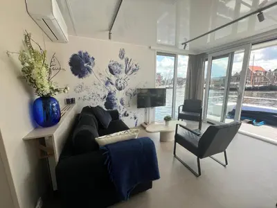 a living room with a black couch and a chair at Bed en B-ootje in Bunschoten