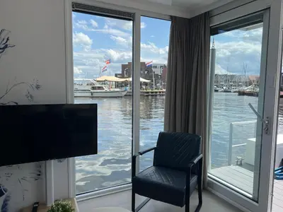 a room with a window with a chair and a television at Bed en B-ootje in Bunschoten
