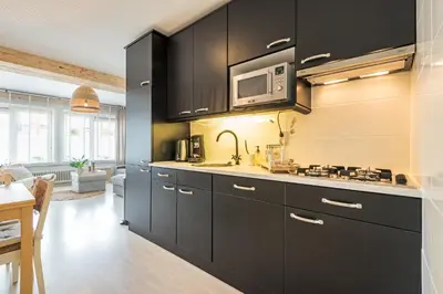 a kitchen with black cabinets and a microwave at Beachhouse Jula in Egmond aan Zee