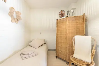 a small room with a bed and a chair at Beachhouse Jula in Egmond aan Zee