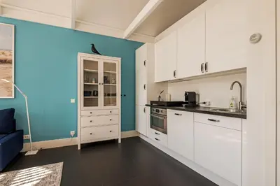 a kitchen with white cabinets and a blue wall at Dune Haven in Schoorl