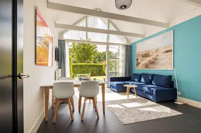 a living room with a blue couch and a table at Dune Haven in Schoorl