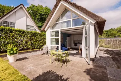 a garden with a patio with a table and chairs at Dune Haven in Schoorl