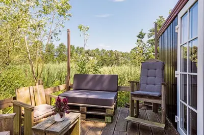 a porch with two chairs and a table and a window at Nature lovers Amsterdam Zaandam in Wijdewormer