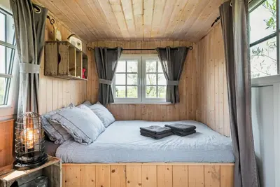 a bed in a tiny house with a window at Nature lovers Your own island in Wijdewormer
