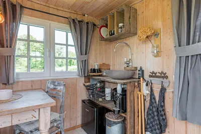 a kitchen with wooden walls and a sink and a table at Nature lovers Your own island in Wijdewormer