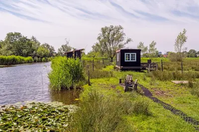 a cabin on the side of a river at Nature lovers Your own island in Wijdewormer